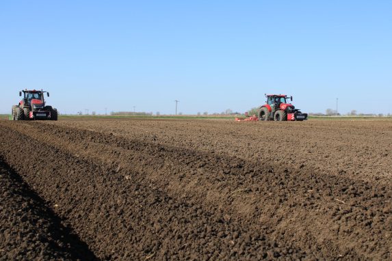 2 red glover tractors working in the field for seed-bed-prep